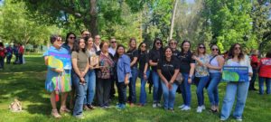 Laura's family and Monarch Service staff posting with the Visionary Voice Award and Equity in Action posters.