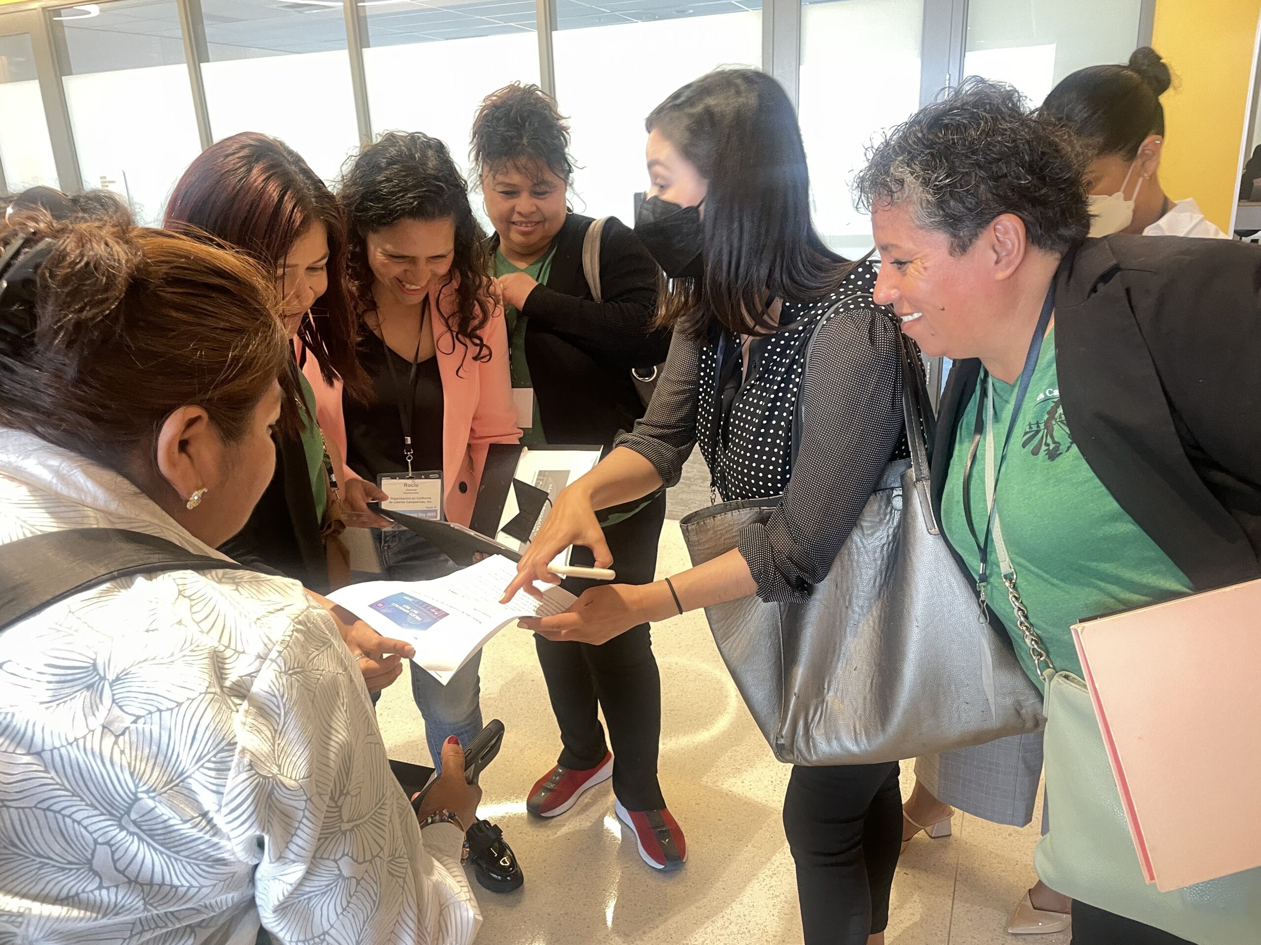 Women from Líderes Campesinas standing in a circle with one individual pointing to a document.