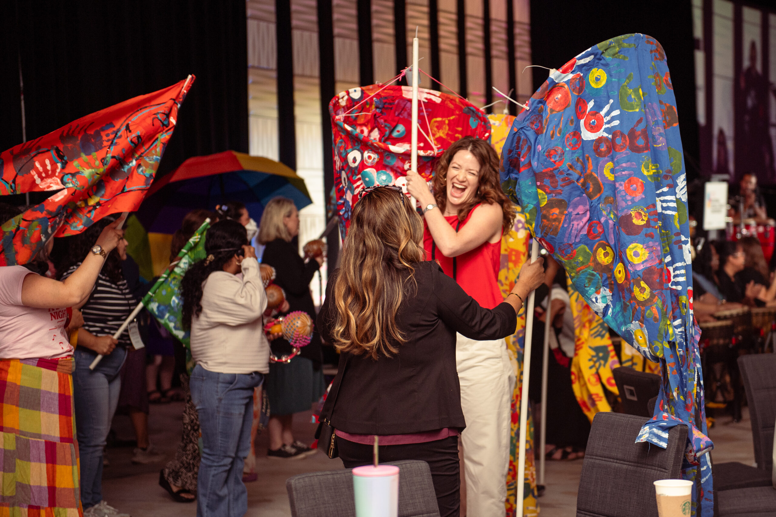 Photo of conference attendees dancing to Drummers Without Borders' performance, holding various items.